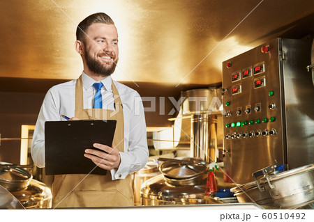 Adult engineer inspecting process of brewing beer. 60510492