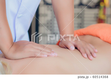 close-up of hands of a masseur massaging back of a young asian woman. 60514368