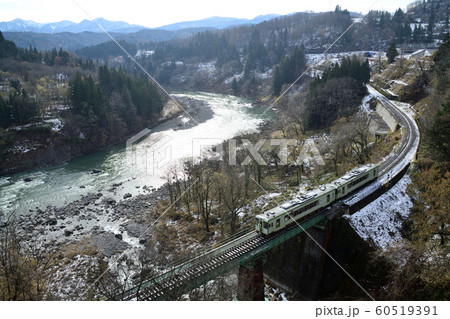 初冬の千曲川沿いを走る飯山線のローカル列車 60519391