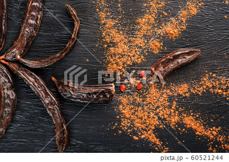 Carob fruit on a black textured background in the Carob fruit on a black textured background in the 60521244