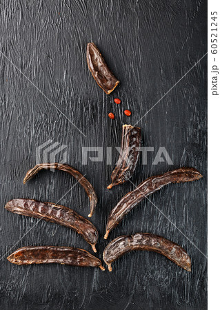 Carob fruit on a black textured background in the 60521245