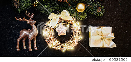 Christmas or New Year decorations on a dark background: Christmas tree, gold decorations, reindeer, garland, gift 60521502