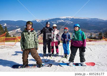 Group of smiling people on skis and snowboard in deep snow on background of winter mountains. Group of smiling people on skis and snowboard in deep snow on background of winter mountains. 60526177