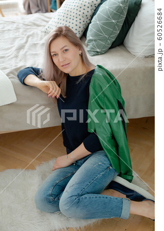 Blonde woman is sitting near the cozy bed 60526684
