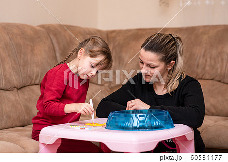 Little girl makes art toy from fusible colorful beads. Mom inspires her daughter. Toy that develops 60534477