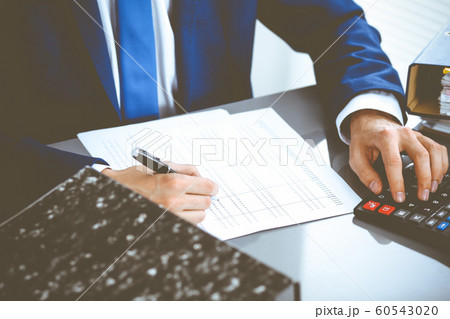 Bookkeeper or financial inspector hands making report, calculating or checking balance. Internal Revenue Service inspector man checking financial document. Business, tax and audit concepts Bookkeeper or financial inspector hands making report, calculating or checking balance. Internal Revenue Service inspector man checking financial document. Business, tax and audit concepts 60543020