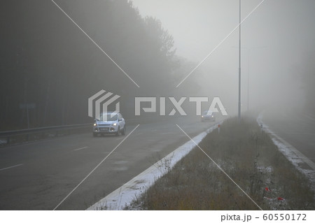 Cars in the fog. Bad winter weather and dangerous automobile traffic on the road. Vehicles in fog. Cars in the fog. Bad winter weather and dangerous automobile traffic on the road. Vehicles in fog. 60550172