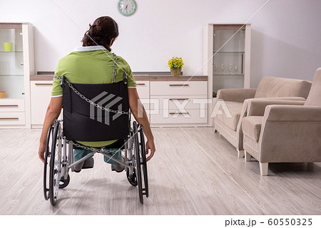 Young male invalid in wheel-chair suffering at home 60550325