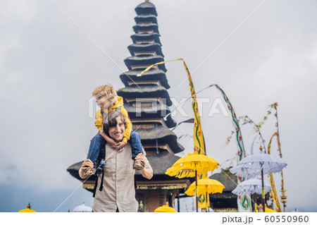 Dad and son in the background of Pura Ulun Danu Bratan, Bali. Hindu temple surrounded by flowers on Bratan lake, Bali. Major Shivaite water temple in Bali, Indonesia. Hindu temple. Traveling with Dad and son in the background of Pura Ulun Danu Bratan, Bali. Hindu temple surrounded by flowers on Bratan lake, Bali. Major Shivaite water temple in Bali, Indonesia. Hindu temple. Traveling with 60550960