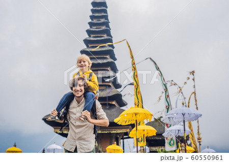 Dad and son in the background of Pura Ulun Danu Bratan, Bali. Hindu temple surrounded by flowers on Bratan lake, Bali. Major Shivaite water temple in Bali, Indonesia. Hindu temple. Traveling with Dad and son in the background of Pura Ulun Danu Bratan, Bali. Hindu temple surrounded by flowers on Bratan lake, Bali. Major Shivaite water temple in Bali, Indonesia. Hindu temple. Traveling with 60550961