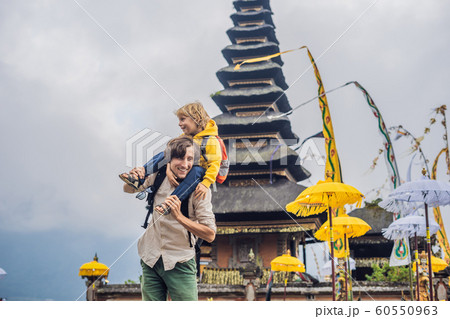 Dad and son in the background of Pura Ulun Danu Bratan, Bali. Hindu temple surrounded by flowers on Bratan lake, Bali. Major Shivaite water temple in Bali, Indonesia. Hindu temple. Traveling with Dad and son in the background of Pura Ulun Danu Bratan, Bali. Hindu temple surrounded by flowers on Bratan lake, Bali. Major Shivaite water temple in Bali, Indonesia. Hindu temple. Traveling with 60550963