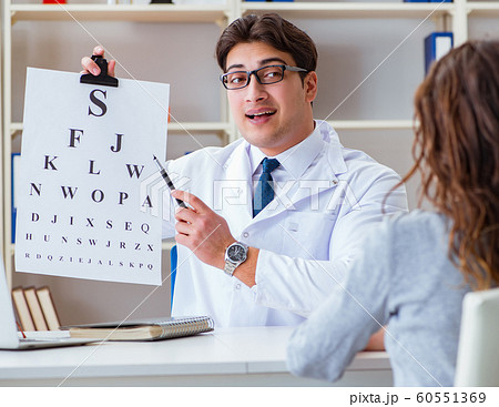 Doctor optician with letter chart conducting an eye test check Doctor optician with letter chart conducting an eye test check 60551369