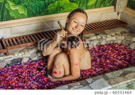 Attractive Young woman in bath with petals of tropical flowers and aroma oils. Spa treatments for skin rejuvenation. Alluring woman in Spa salon. Luxury spa and skin care 60551464