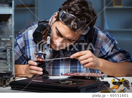 The repairman trying to repair laptop with miscroscope 60551601
