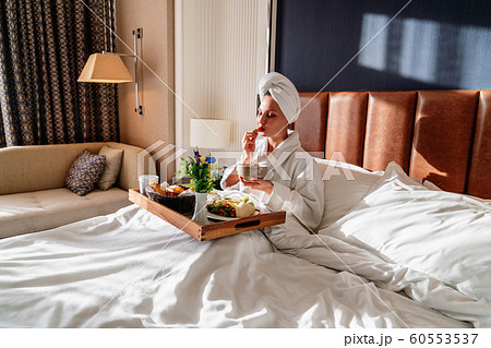 young woman having her breakfast in bed with pleasure young woman having her breakfast in bed with pleasure 60553537