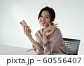椅子に座ってスマートフォンを持ちながらOKサインを出す女性・横位置 60556407