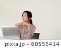 パソコンの前で指を組みながら考え事をする女性 60556414