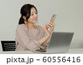 パソコンの前でスマートフォンを触る女性 60556416