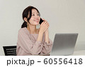パソコンの前でスマートフォンで楽しそうに電話する女性 60556418