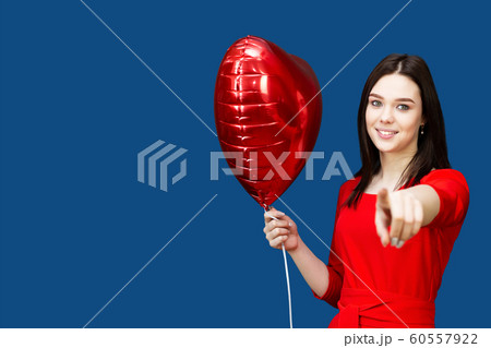 Girl in a red dress shows a finger at the camera. 60557922