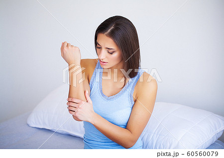 Pain hand. Sad woman with pain in hand at home 60560079