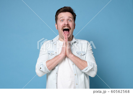 Emotional excited young man exclaiming in shock and full disbelief, gesturing actively. 60562568