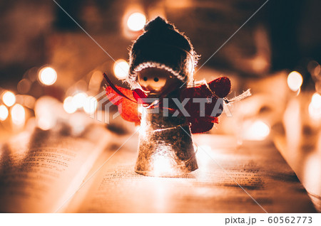 wooden angel christmas garland stands on a book, in the background is an LED garland. Christmas holidays concept. wooden angel christmas garland stands on a book, in the background is an LED garland. Christmas holidays concept. 60562773