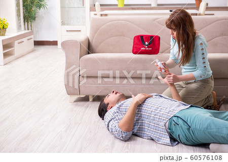 Young couple in first aid concept at home 60576108