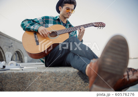 Musician playing the guitar near the river Musician playing the guitar near the river 60576276