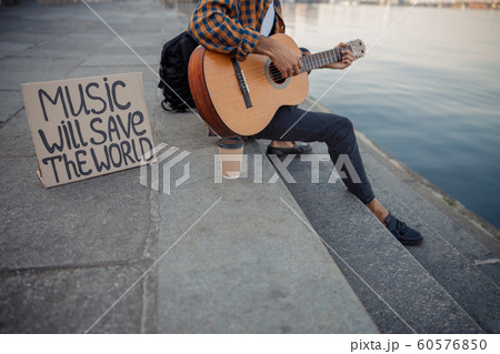Musician playing guitar while resting near river Musician playing guitar while resting near river 60576850