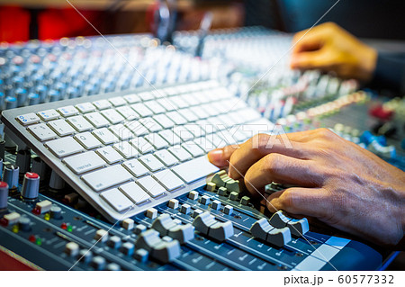 male producer, sound engineer hands pressing computer keyboard on audio mixing concole in recording, broadcasting studio 60577332
