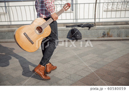 Young guy with guitar walking along the street Young guy with guitar walking along the street 60580059