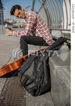 Smiling young guy resting with coffee outdoors 60580262
