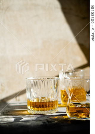 Whiskey in glasses on table in bright sunlight, yellow drink Whiskey in glasses on table in bright sunlight, yellow drink 60580586