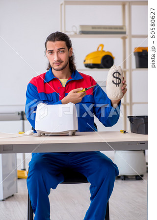 Young male contractor repairing toaster at workshop 60580627