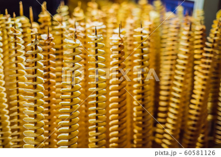 Spiral potatoes fried, on wooden sticks, spiral. Selling food at the market. Unhealthy fried food. Street food, a spiral fried potato on a stick 60581126