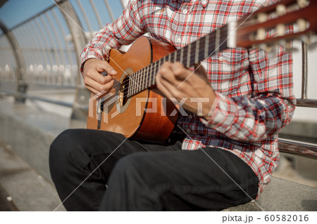 Musician playing guitar and sitting in the city Musician playing guitar and sitting in the city 60582016