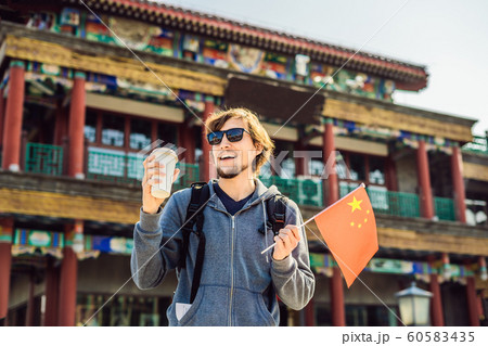 Enjoying vacation in China. Young man with national chinese flag on the background of the old Chinese street. Travel to China concept. Visa free transit 72 hours, 144 hours in China Enjoying vacation in China. Young man with national chinese flag on the background of the old Chinese street. Travel to China concept. Visa free transit 72 hours, 144 hours in China 60583435