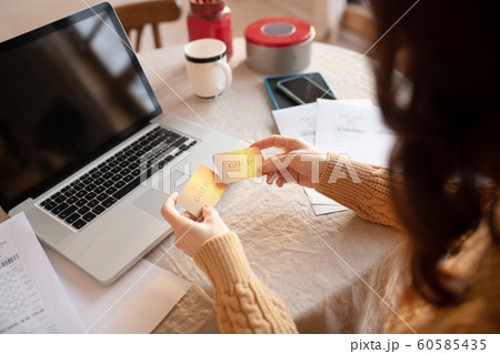 Long-haired young woman in sweater holding a credit card Long-haired young woman in sweater holding a credit card 60585435