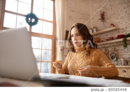 Dark-haired young woman in sweater working on a laptop 60585448