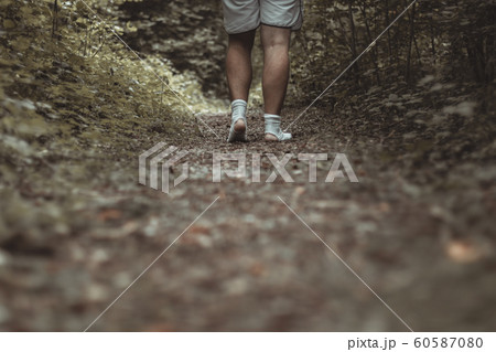 male feet walking with torn socks through a green 60587080