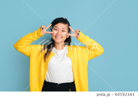 Asian teenager's portrait isolated on blue studio background Asian teenager's portrait isolated on blue studio background 60592383