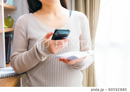 スマホを見ながら計算する女性　悩む 調べる 60592880