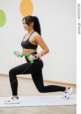 Young athletic girl with dumbbells indoors. Fitness girl workout in the gym 60593298