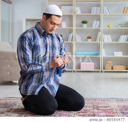 Young muslim man praying at home Young muslim man praying at home 60593477