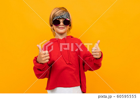 attractive blond boy with a bandana on his head in a red sweater and glasses shows a class on an attractive blond boy with a bandana on his head in a red sweater and glasses shows a class on an 60595555