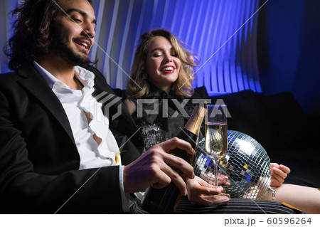 Happy young man with bottle of champagne going to pour wine into flute 60596264