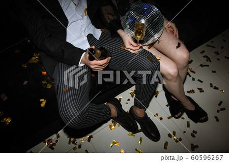 Legs of young couple toasting with flutes of champagne while resting on couch 60596267