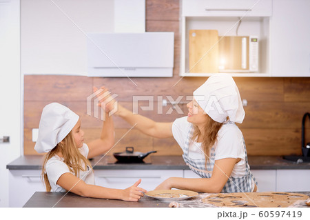 mother and daughter clapping hands with each other in kitchen 60597419