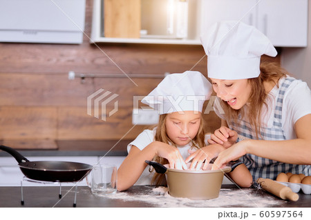 mother making dough with daughter in kitchen mother making dough with daughter in kitchen 60597564